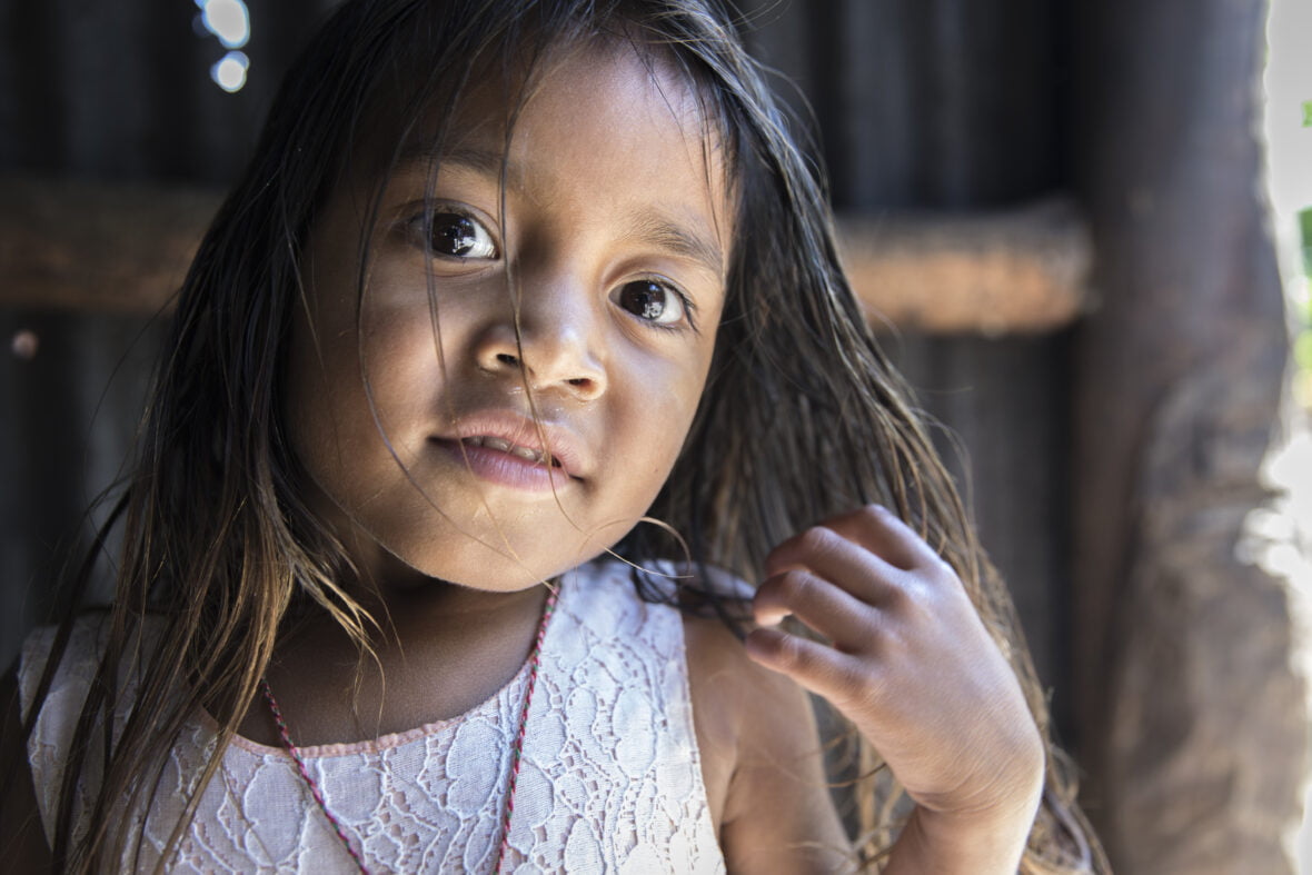 Itätimorilainen nuori tyttö Zelita haroo hiuksiaan ja katsoo kameraan.