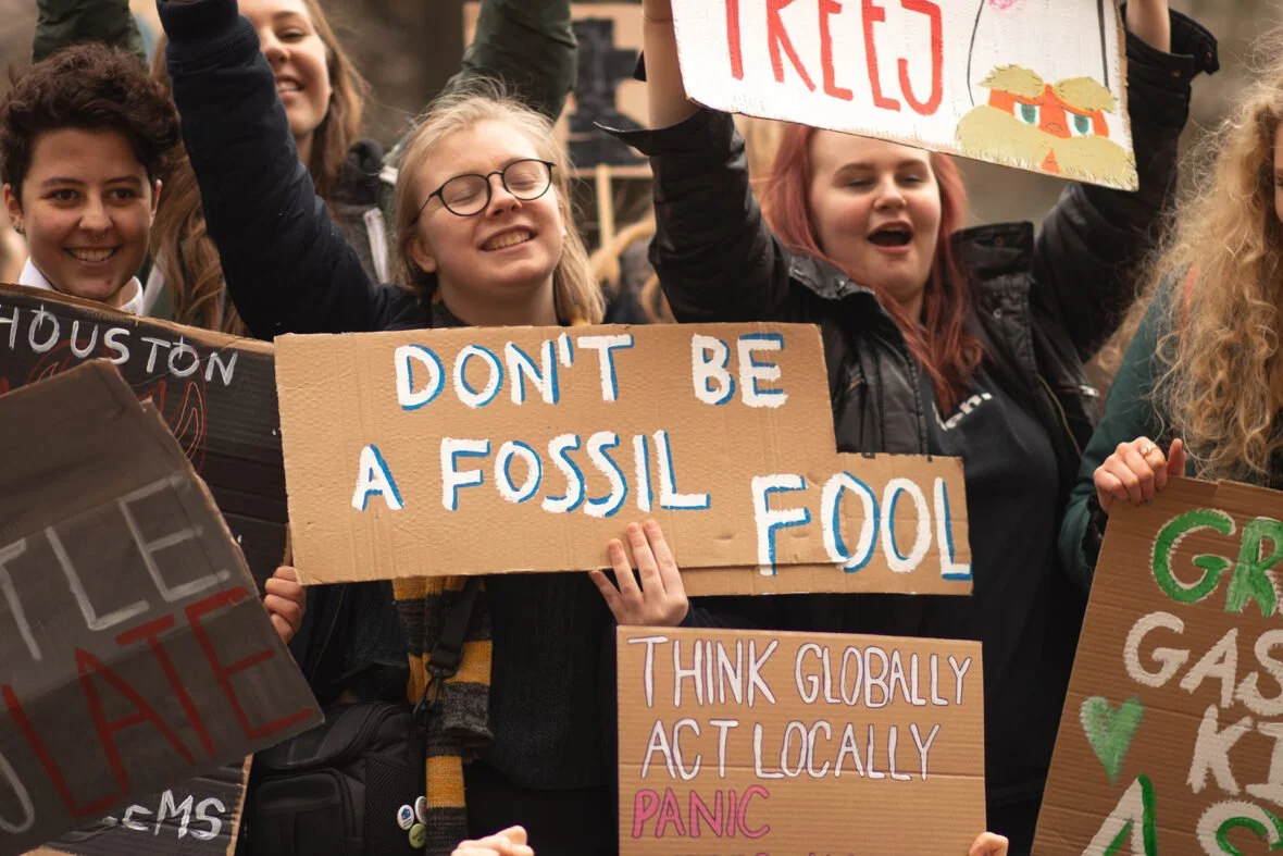 Nuoret pitelevät mielenosoituksessa kylttejä, joista yhdessä lukee don't be a fossil fool.