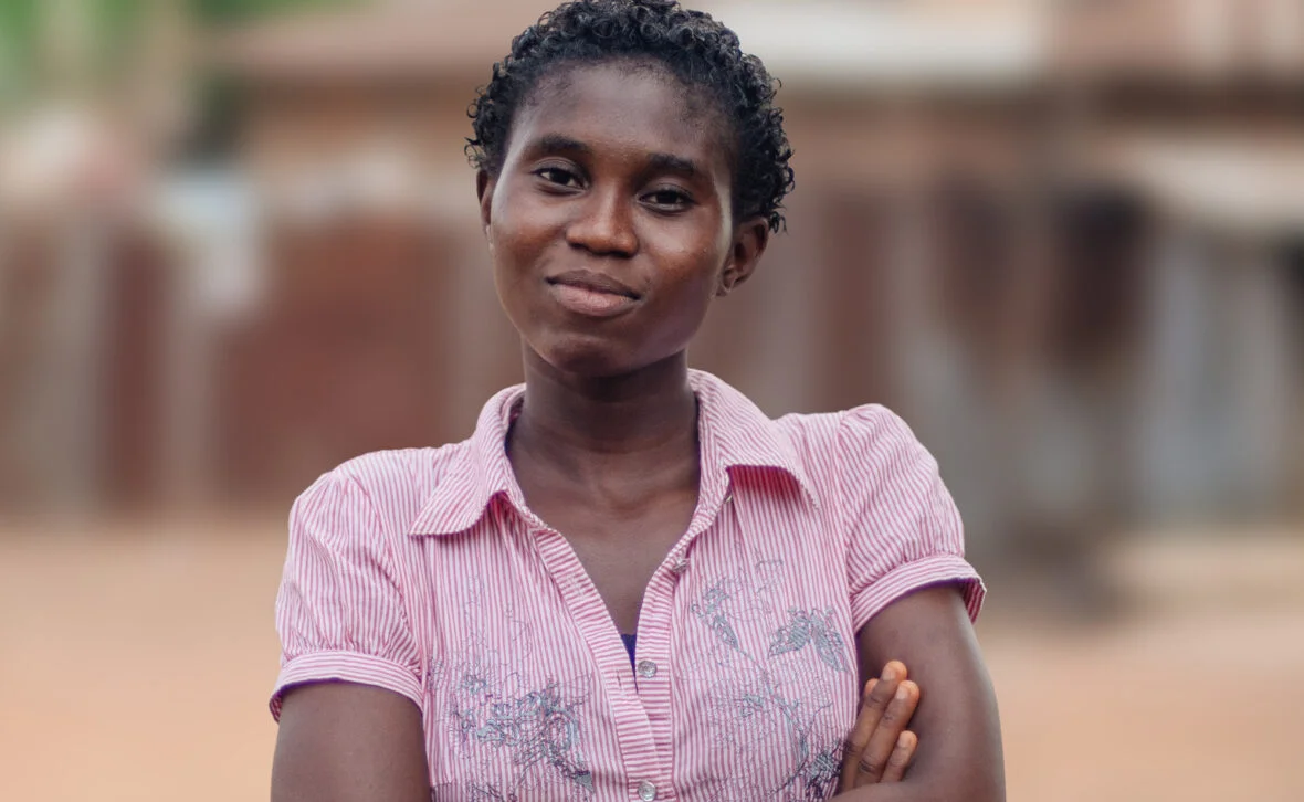 Sierraleoneilainen tyttö seisoo ulkona ja katsoo kameraan.