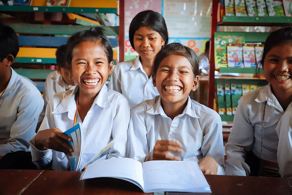 Kambodzalaiset tytöt nauravat koululuokassa.