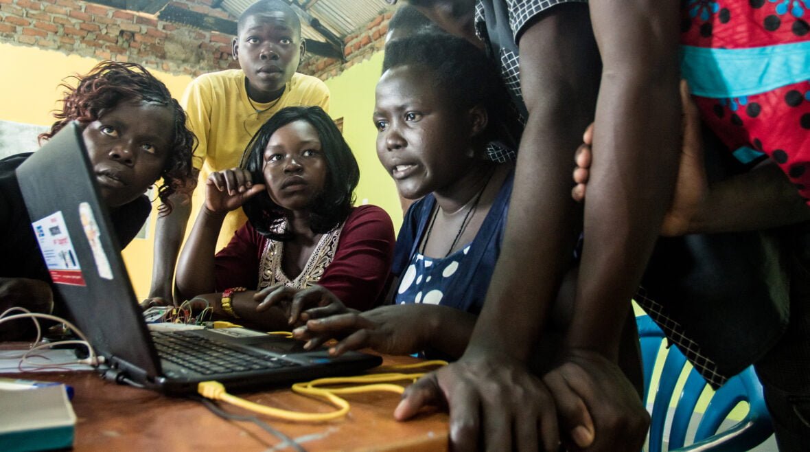 Nuoria tietokonetta käyttämässä Ugandassa.