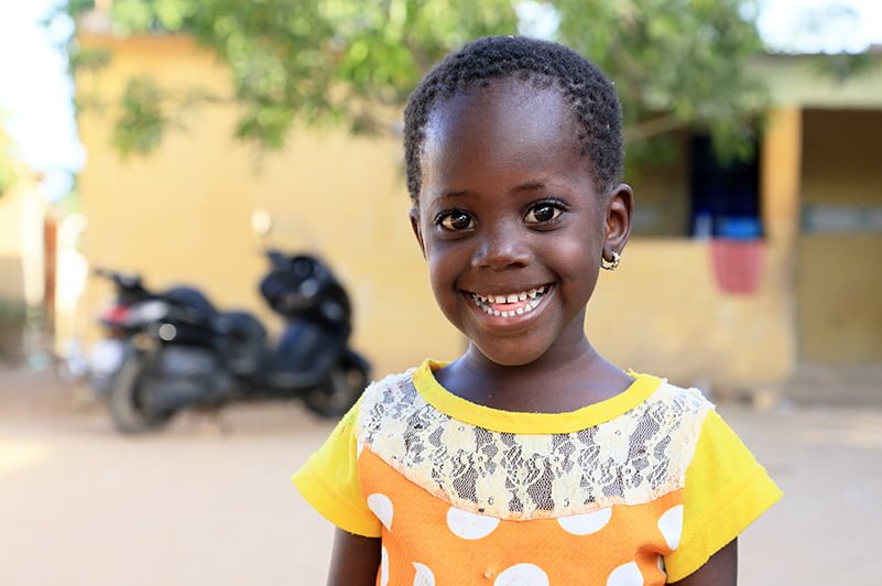 Senegalilainen tyttö hymyilee kameralle.