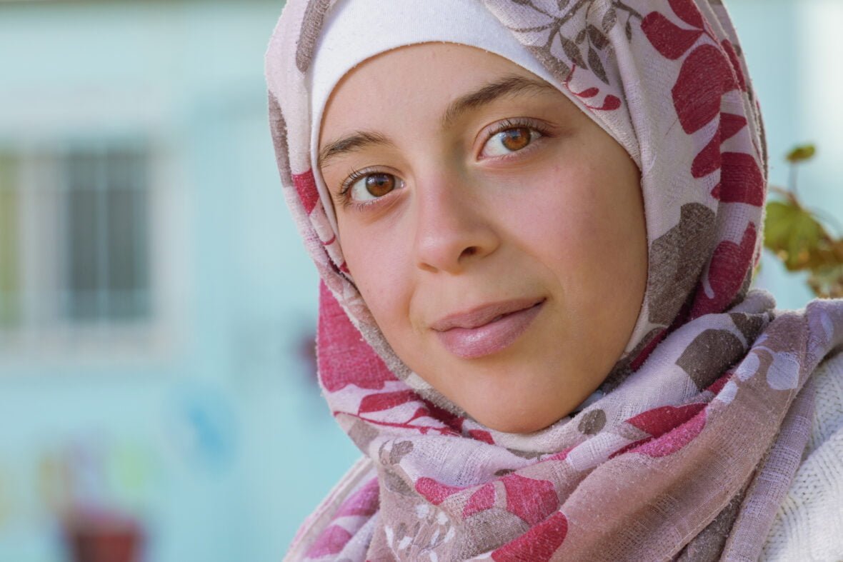 Syyrialainen tyttö hymyilee kameralle.