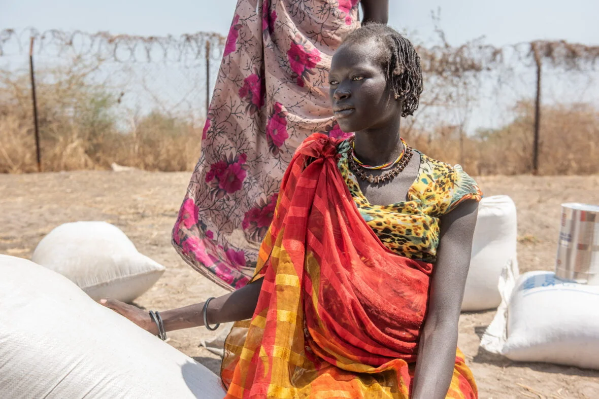 Eteläsudanilainen Adengin istuu keskellä ruokasäkkejä ja kuivaa maaperää.