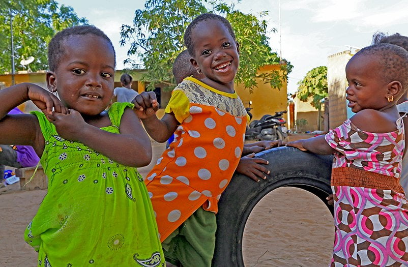 Senegalilaisia pikkulapsia leikkimässä ulkona.