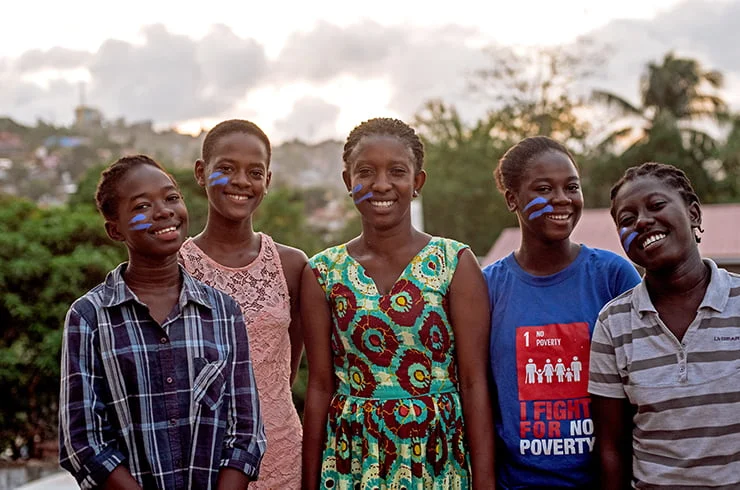 Ryhmä sierraleonelaisia nuoria poseeraa kameralle maiseman edessä.