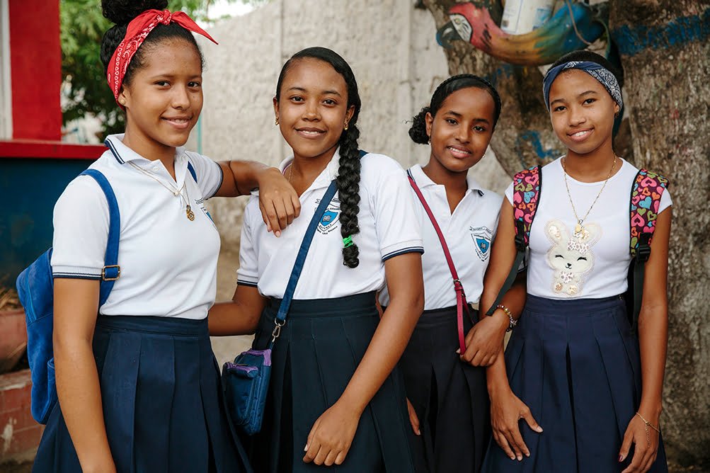 Neljä tyttöä seisoo rinnakkain koulupuvuissa.