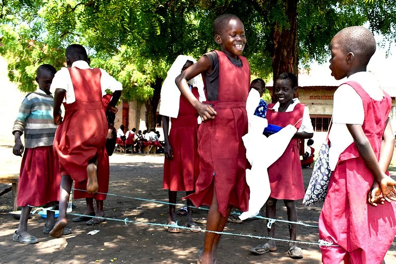 Eteläsudanilaiset tytöt hyppivät hyppynarua yhdessä.