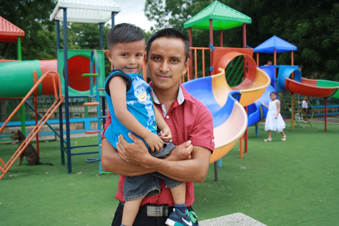 Ecuadorilainen isä pitelee lastaan sylissä leikkipuistossa.l