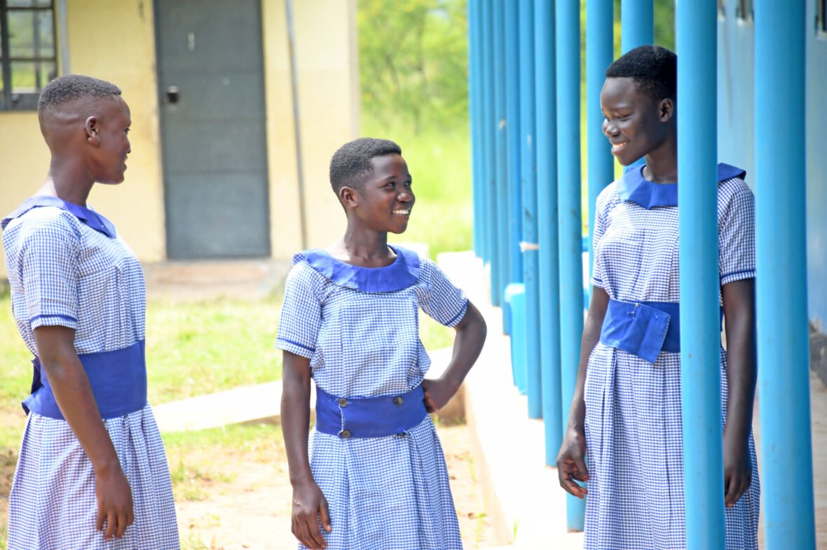 Kolme tyttöä koulun pihalla Ugandassa