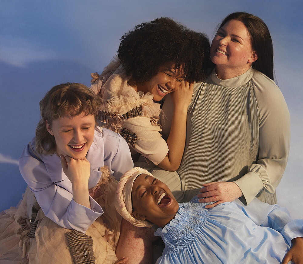Neljä tyttöä makaa sylikkäin ja nauraa, tyttösponssina edistät tyttöjen oikeuksia ja kuukautisterveyttä