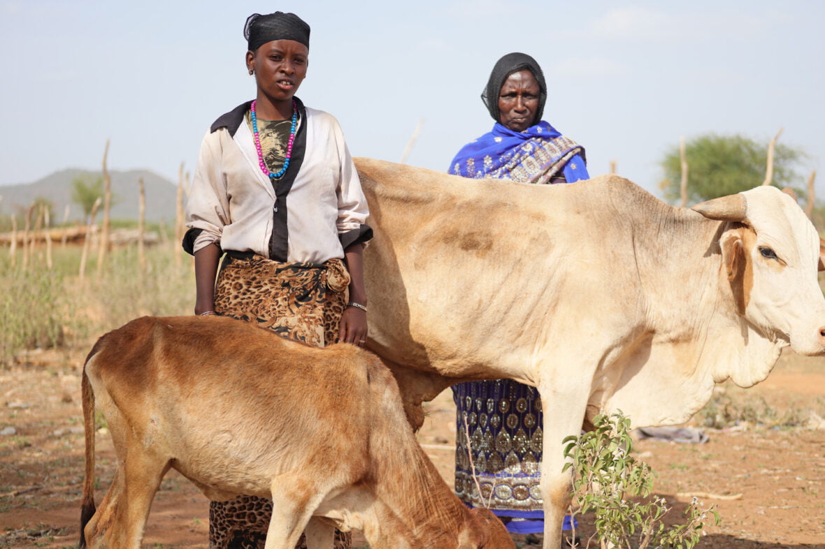 Äiti ja tytär seisovat nälkiintyneen karjan rinnalla.