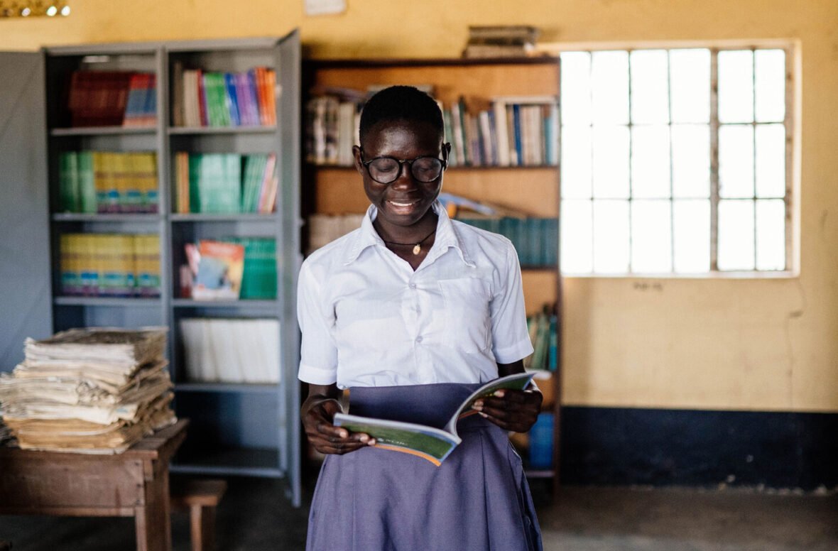 Ugandalainen tyttö pitelee kirjaa kädessään koulussa.