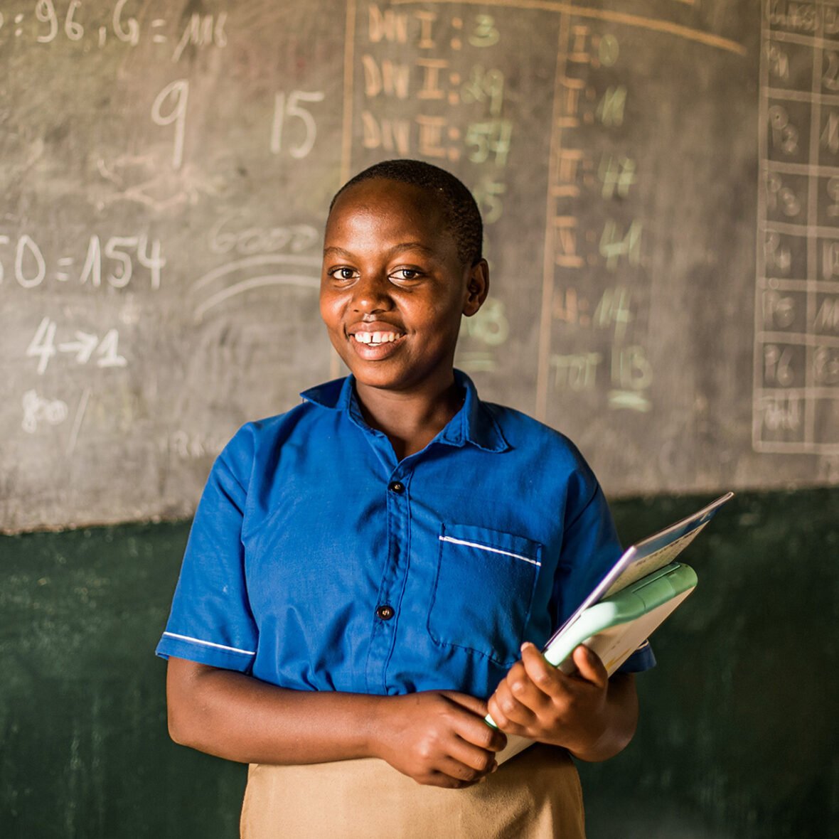 Ruandalainen Olive seisoo koululuokassa.