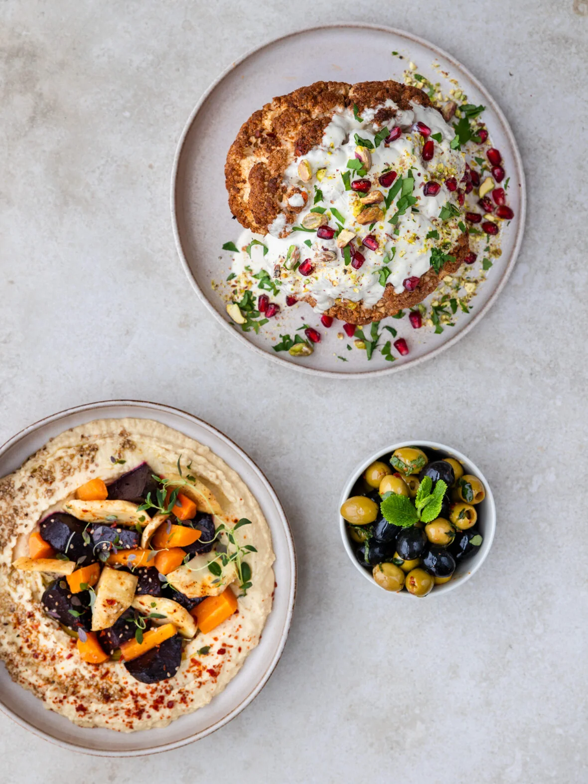 Pöydälle on katettu herkullinen hummus, paahdettu kukkakaali ja raikkaat oliivit.