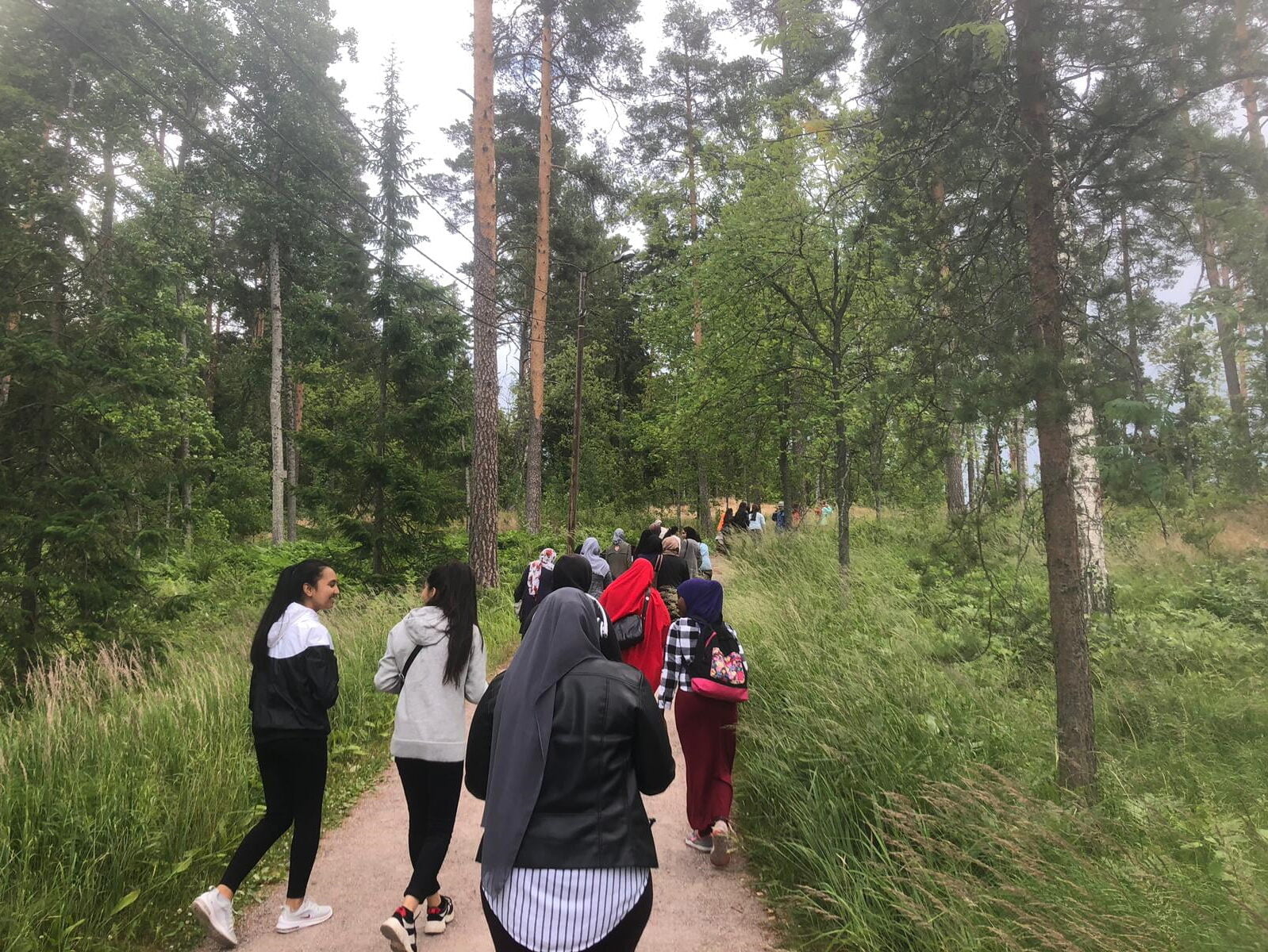 Joukko nuoria kävelee metsäpolkua pitkin.