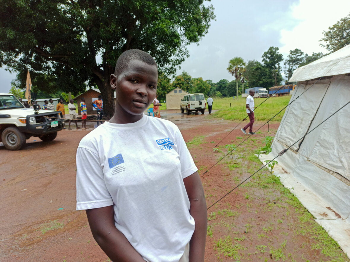 Eteläsudanilainen Alice on vastaanottanut humanitaarista apua Planilta ja seisoo ulkoilmassa avustusteltan vieressä.