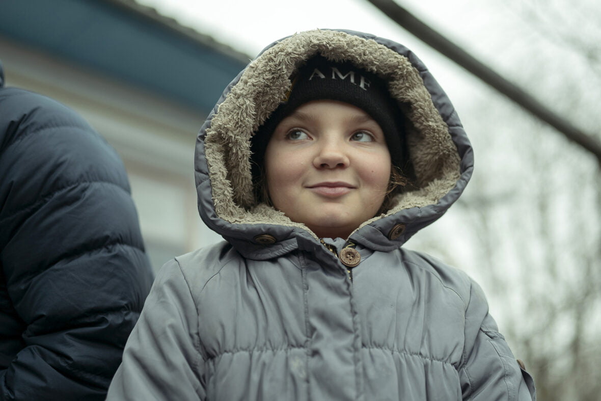 9-vuotias ukrainalainen Natalka-tyttö seisoo kotinsa edessä, päällään paksu talvitakki.