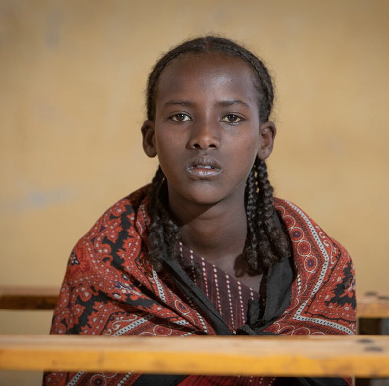 Tyttö istuu tyhjässä koululuokassa ja katsoo suoraan kameraan. Hän elää keskellä pahinta nälkäkriisiä Etiopiassa.