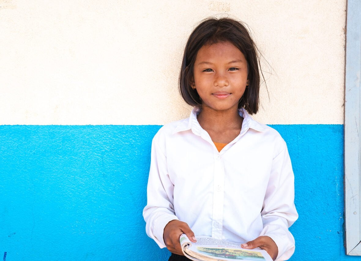 Kambodzalainen Muta seisoo pidellen koulukirjoja käsissään.