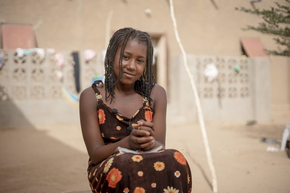 Malilainen Aminata istuu koulukirjoja sylissään.