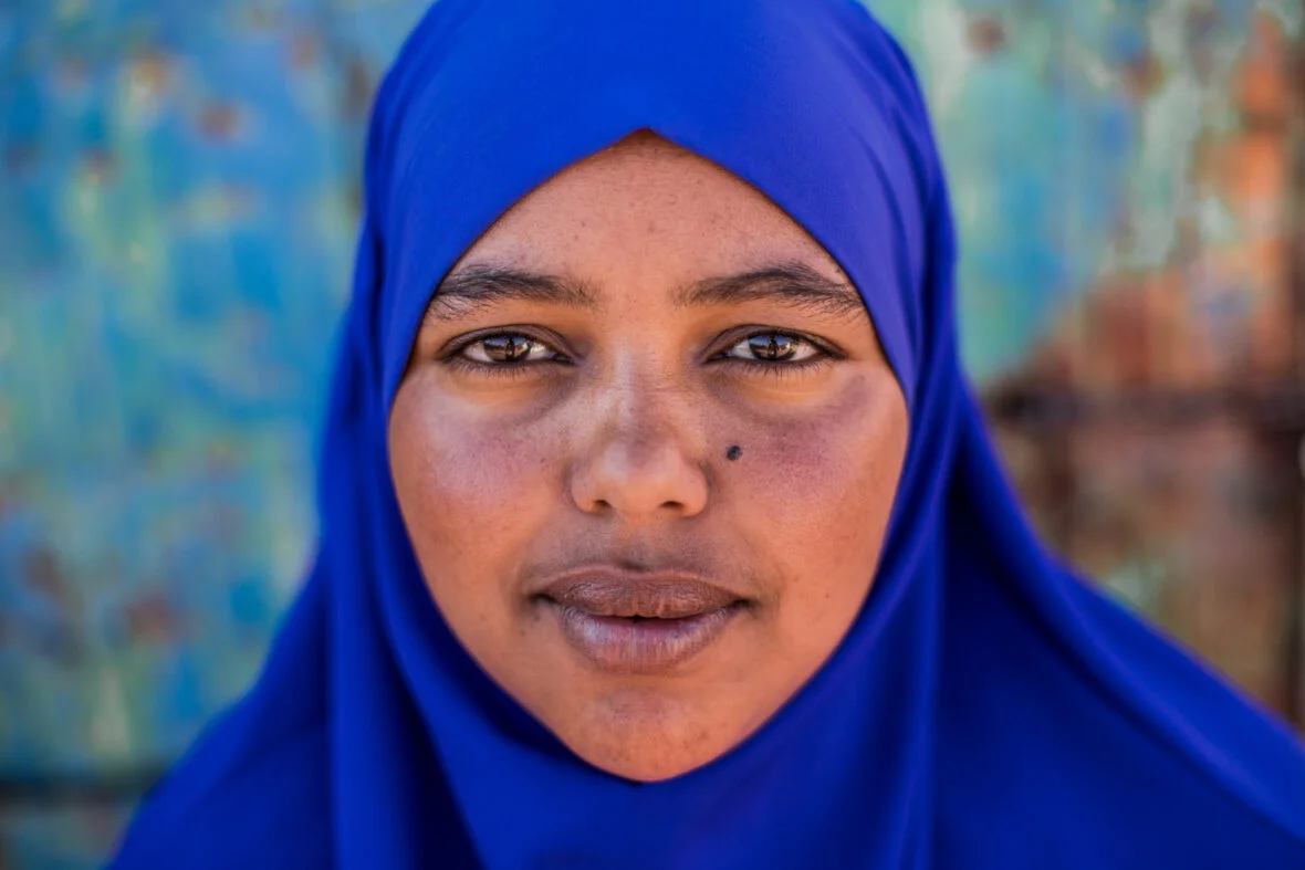 Nuori nainen poseeraa määrätietoisesti kameralle pakolaisleirillä Somaliassa.