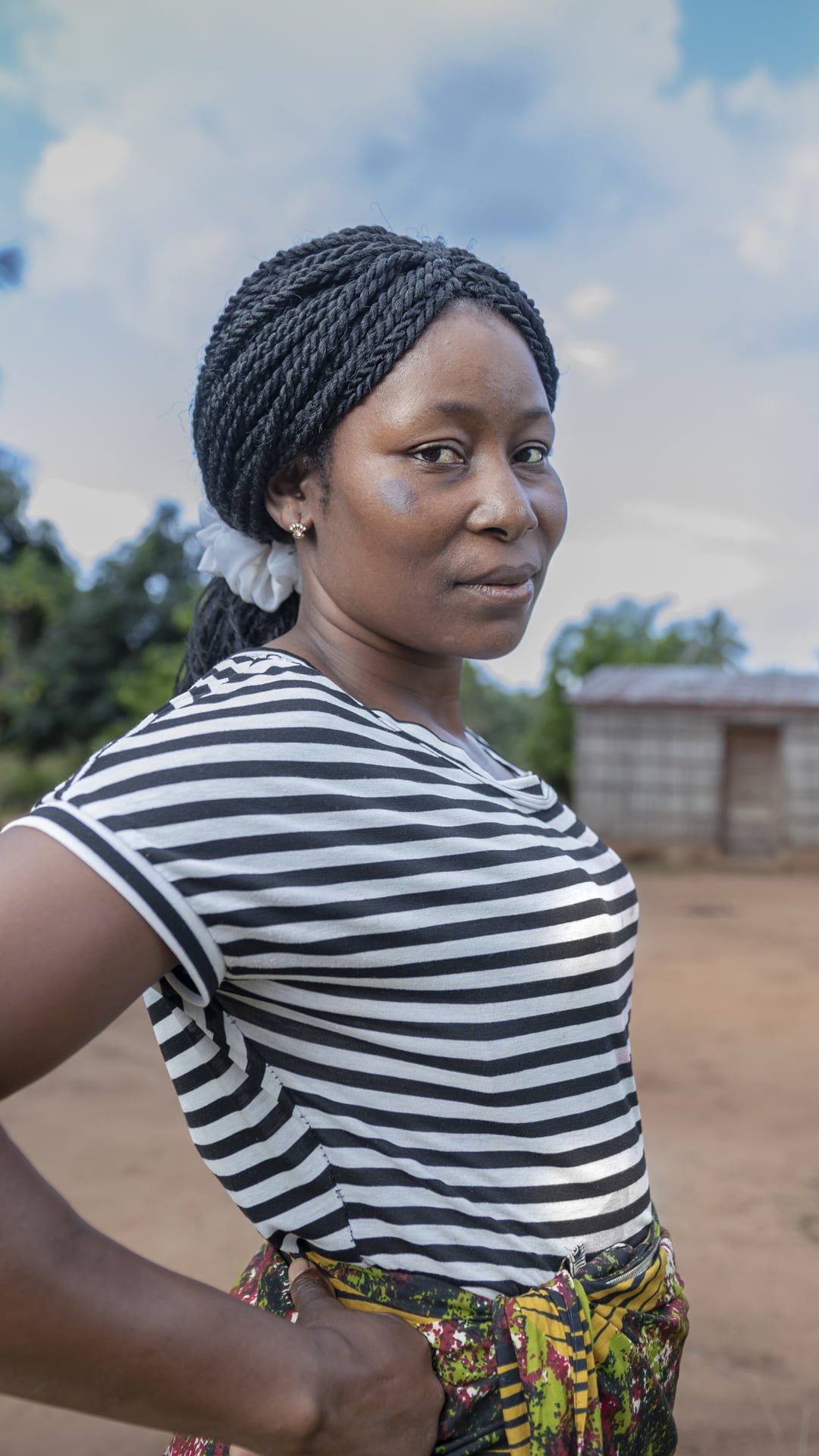 Mosambikilainen Helena seisoo yhteisössään määrätietoisesti kameraan katsoen.