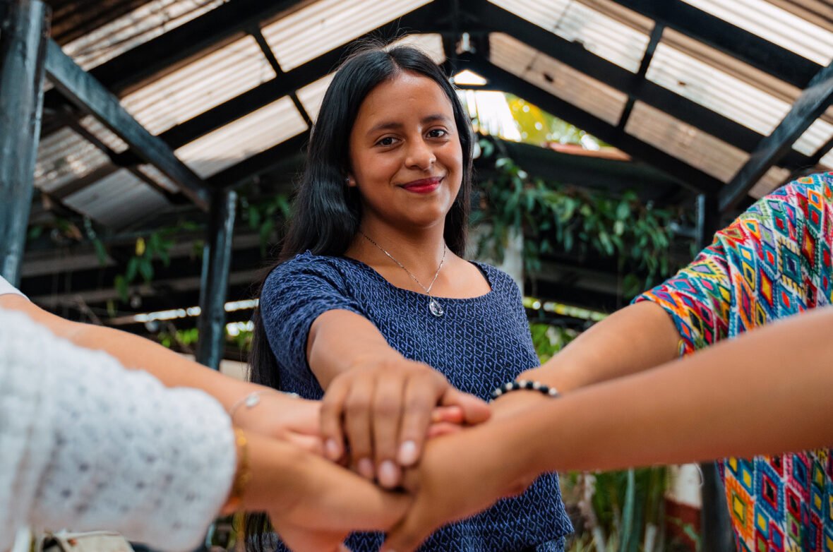 Guatemalalainen nuori nainen on liittänyt kätensä yhteen muiden nuorten kanssa.