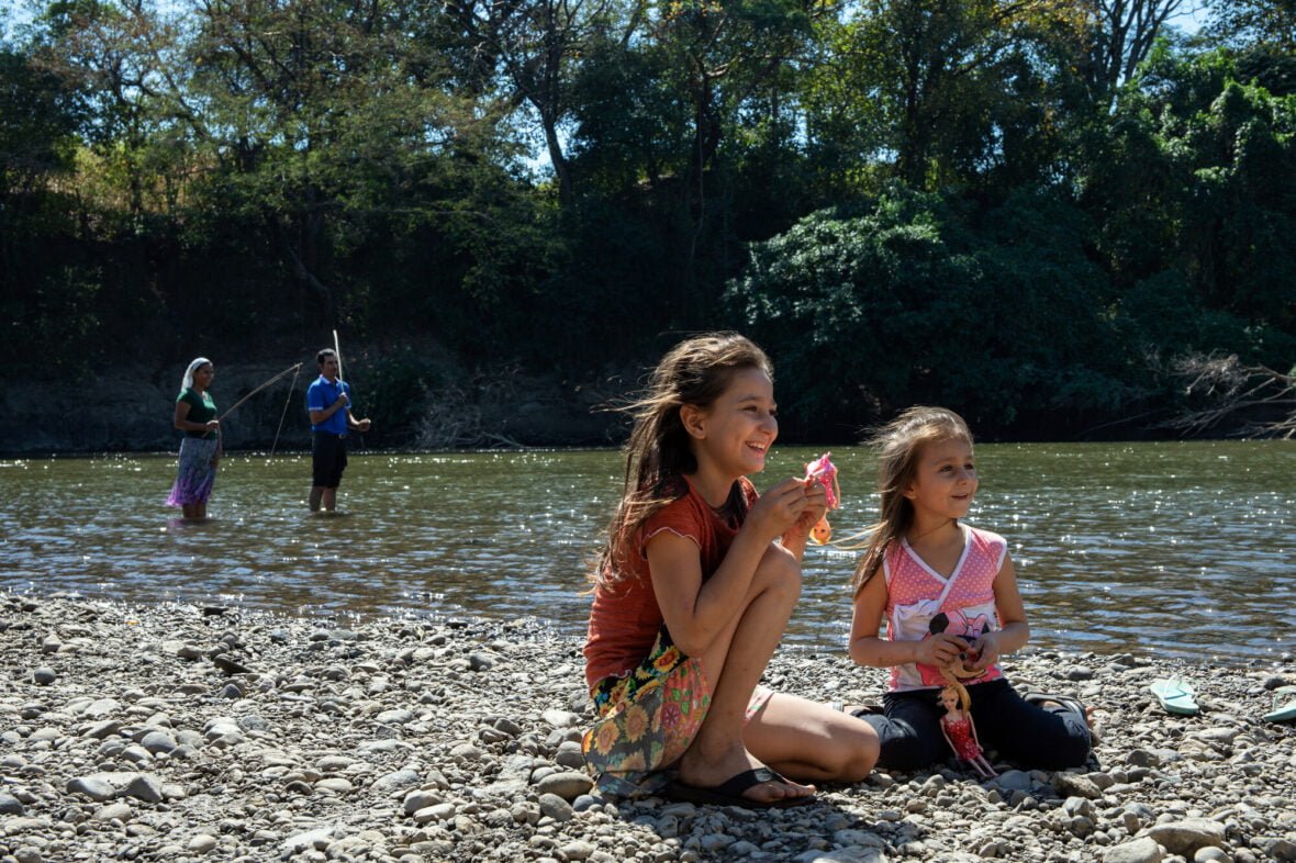 Kaksi tyttöä istuu joen rannalla El Salvadorissa.