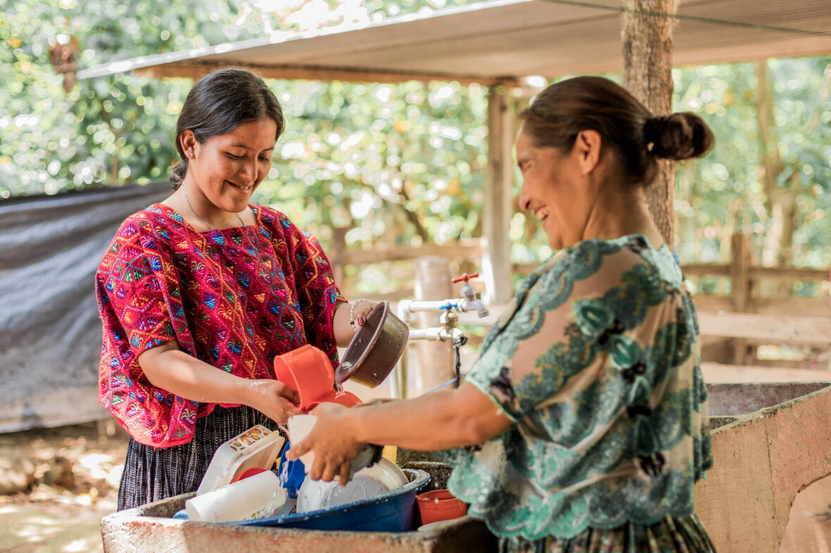 Guatemalalainen Norma, joka on oppinut Planin koulutuksessa kuukautisterveydestä, ja hänen äitinsä pesevät astioita.