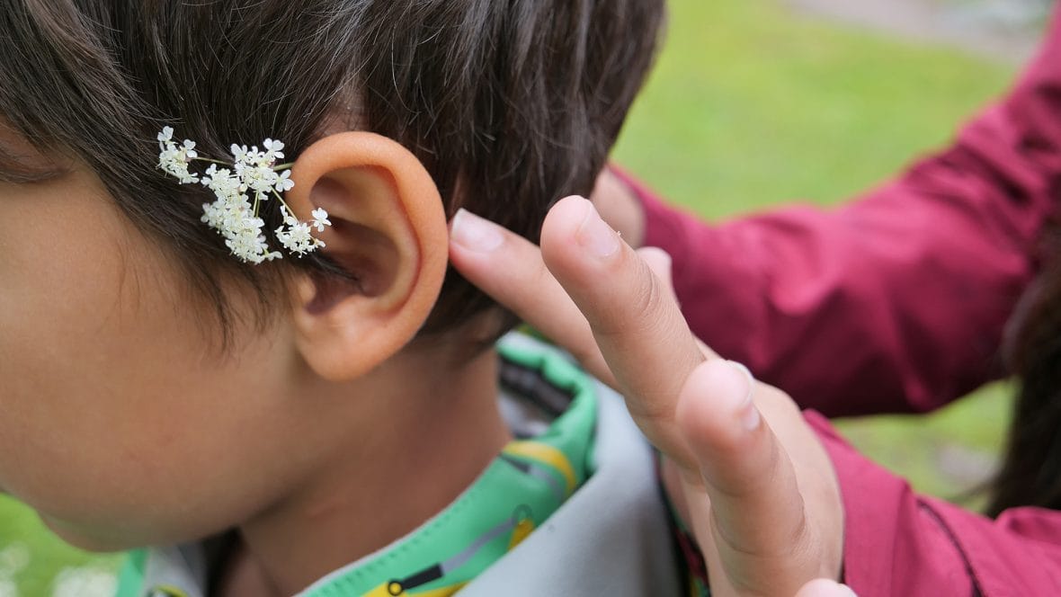 Nuori asettelee kukkasta lapsen korvalle