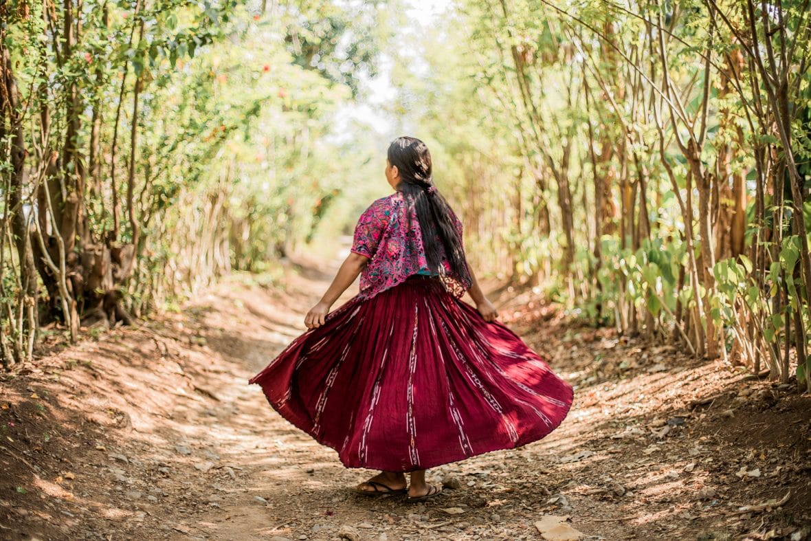 Guatemalalainen nuori nainen kävelee metsätietä pois päin.