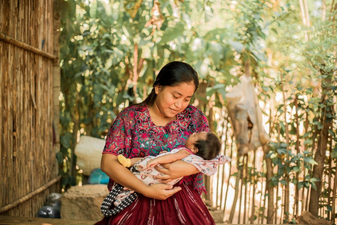 Guatemalalainen Sefora pitää pientä lastaa sylissään.