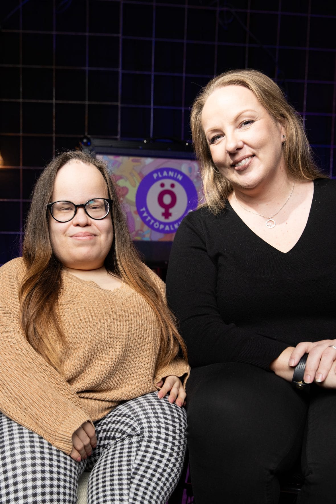 Anniina Lehtinen ja Anni Täckman poseeraavat Planin tyttöpalkinto -logon edessä.