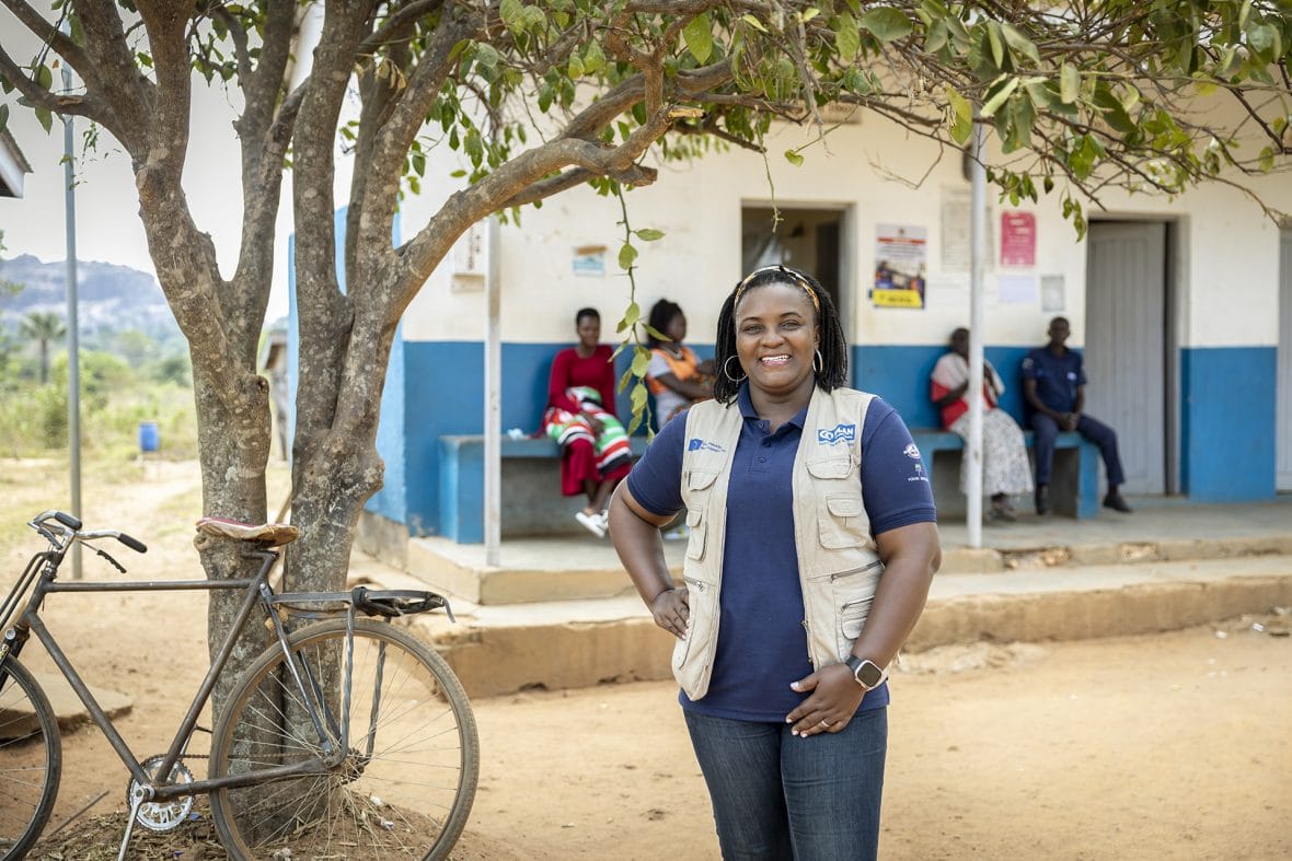 Planin työntekijä Christine Oseku seisoo rakennuksen edessä.