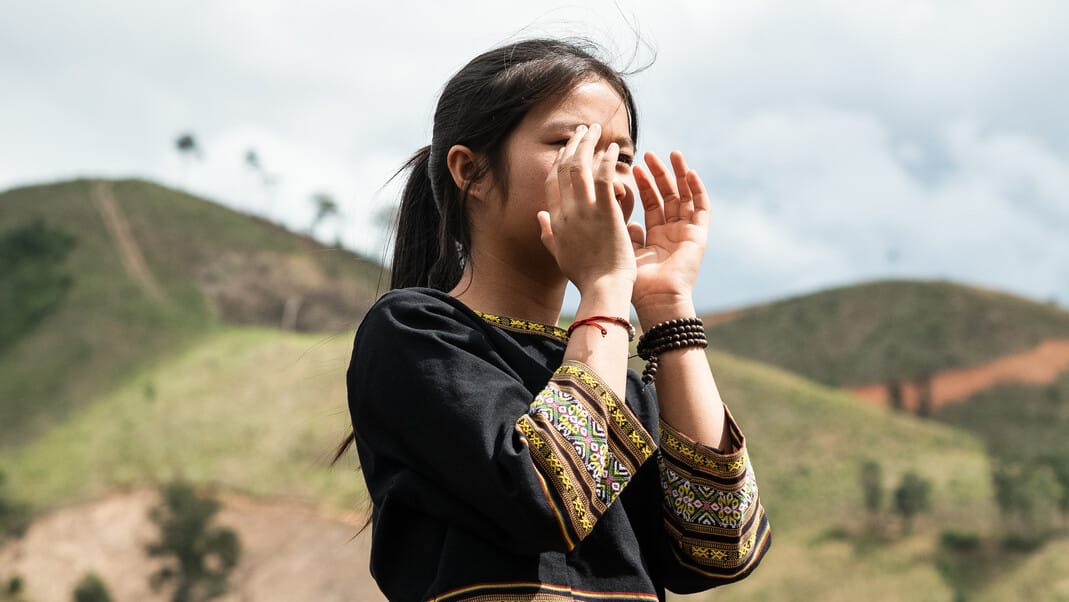 Nuori huutaa kädet suun ympärillä.