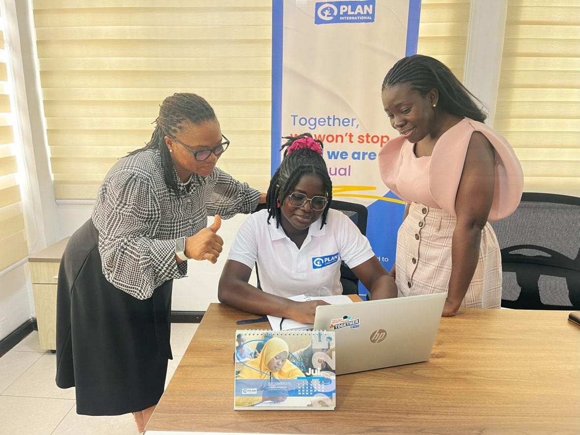 Ghanalainen nuori tietokoneen ääressä, kaksi naista ympärillä opastamassa