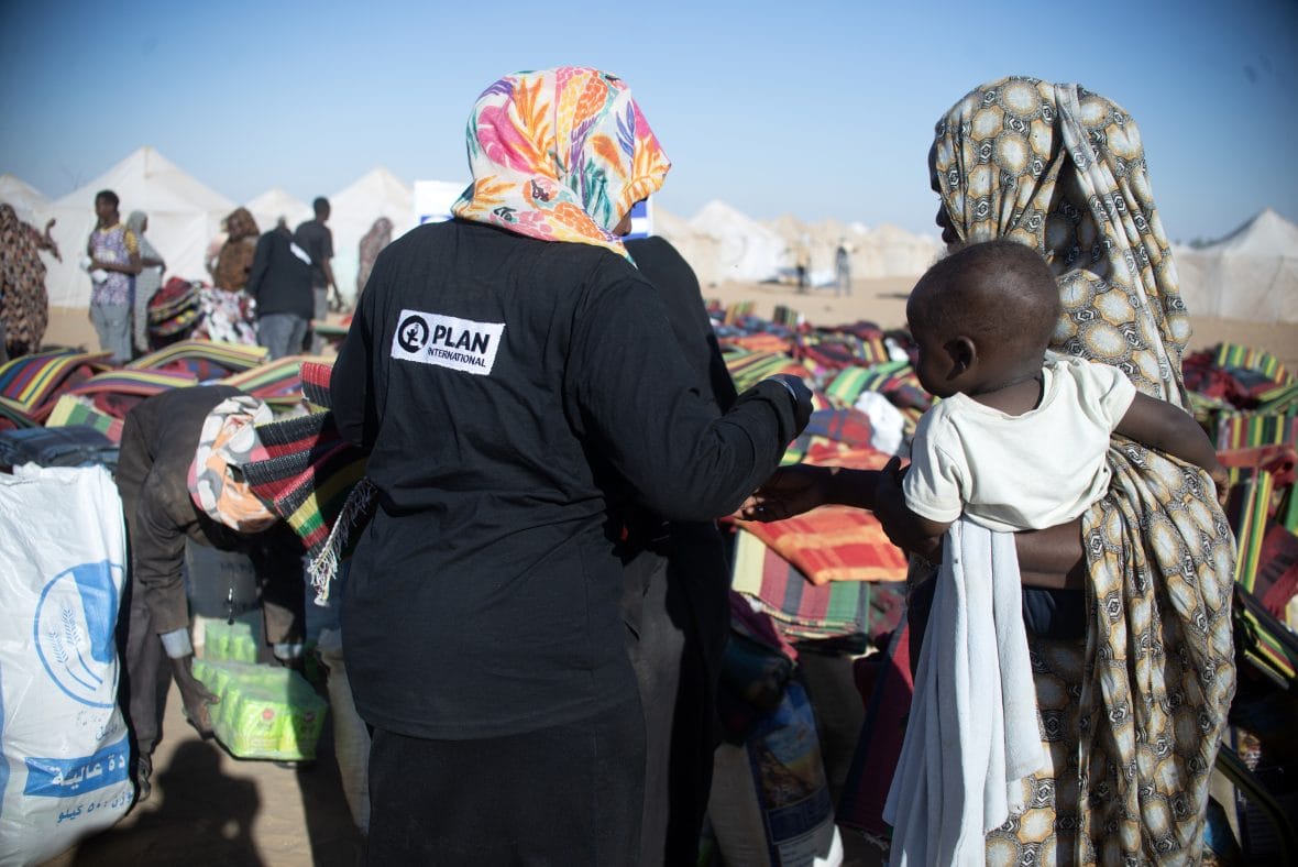 Planin työntekijä jakaa avustustarvikkeita pakolaisleirillä Sudanissa.